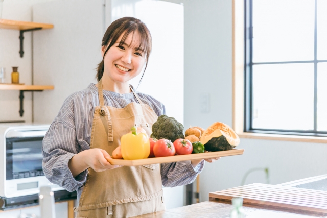 野菜を持ってキッチンに立つ女性